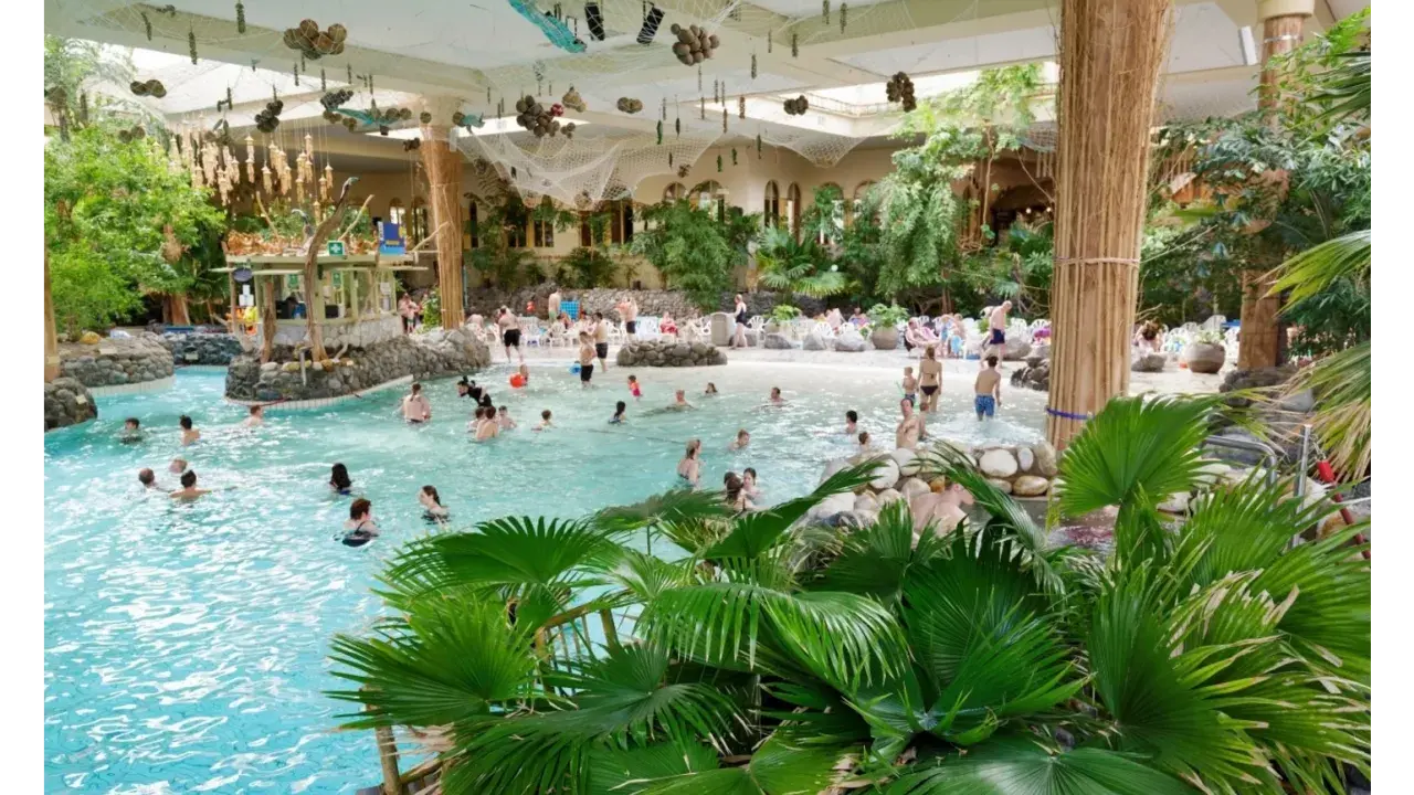 Familien genießen das tropische Ambiente und das Wasser in der **Therme Sauerland**. Palmen und eine Strandbar schaffen Urlaubsfeeling.