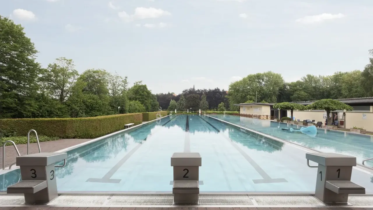 Leeres Freibad Barntrup mit Bahnen und Sprungblöcken. Ein blauer Wal schwimmt im Wasser.