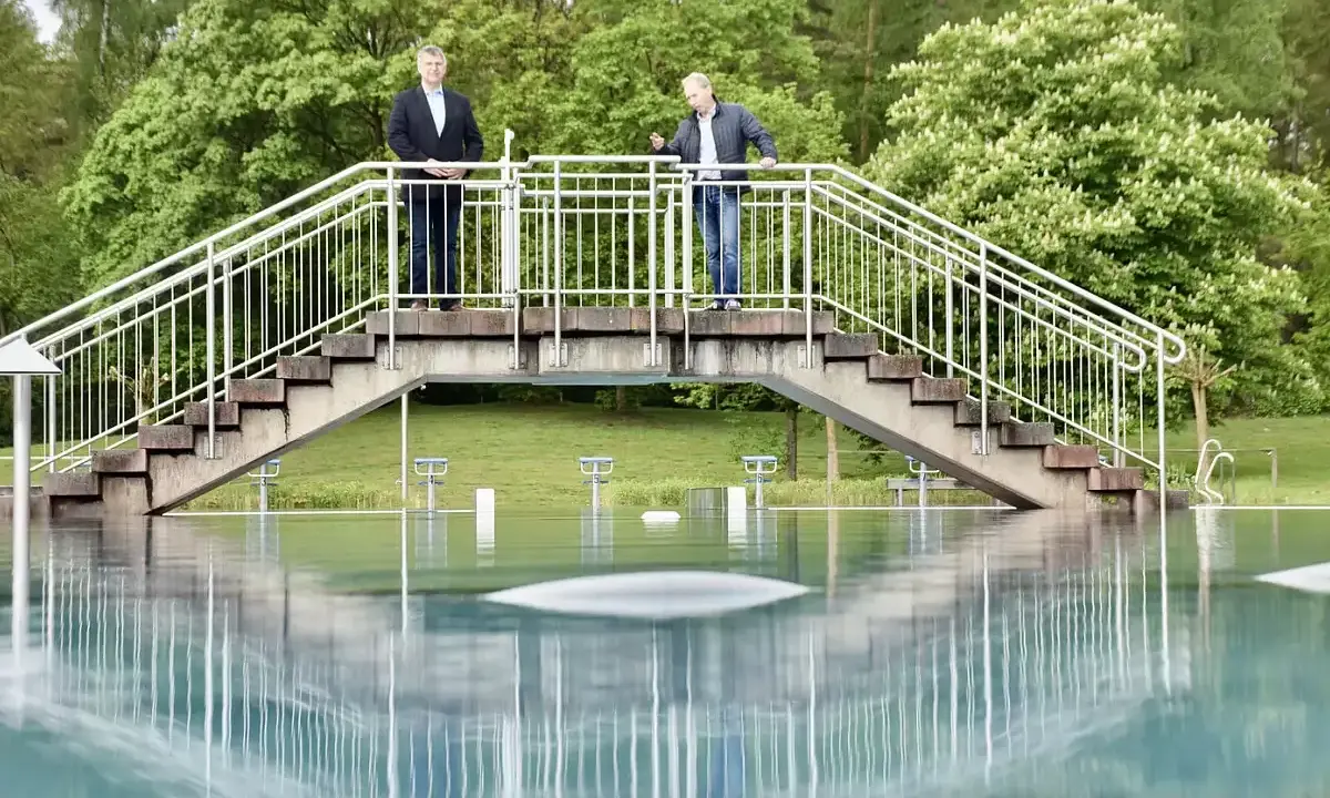 Zwei Männer stehen auf einer Brücke über dem Wasser des Freibad Porta Westfalica.
