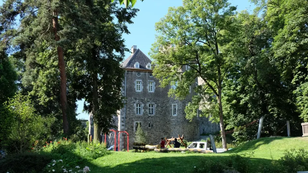 Ein sonniger Tag im Frankenberger Park. Kinder spielen auf einem Spielplatz vor einem alten Gemäuer, umgeben von üppigem Grün.