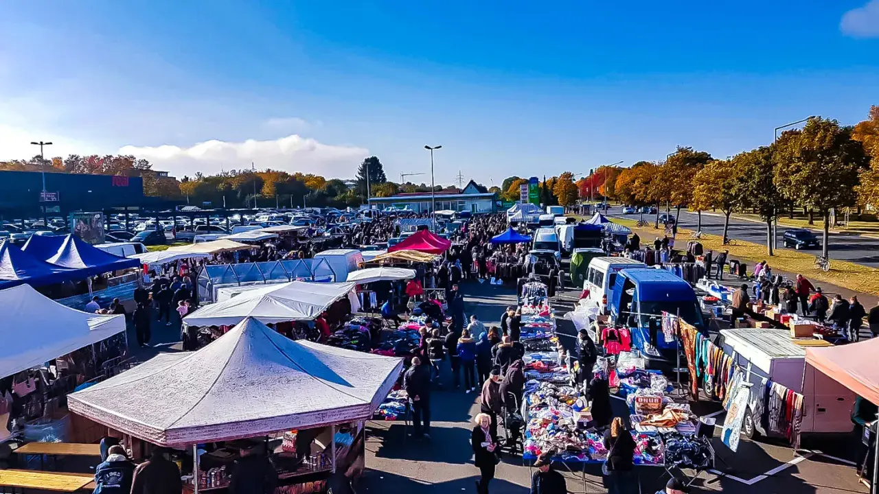 Buntes Treiben auf dem flohmarkt paderborn. Viele Stände mit Kleidung und Trödel unter blauem Himmel.