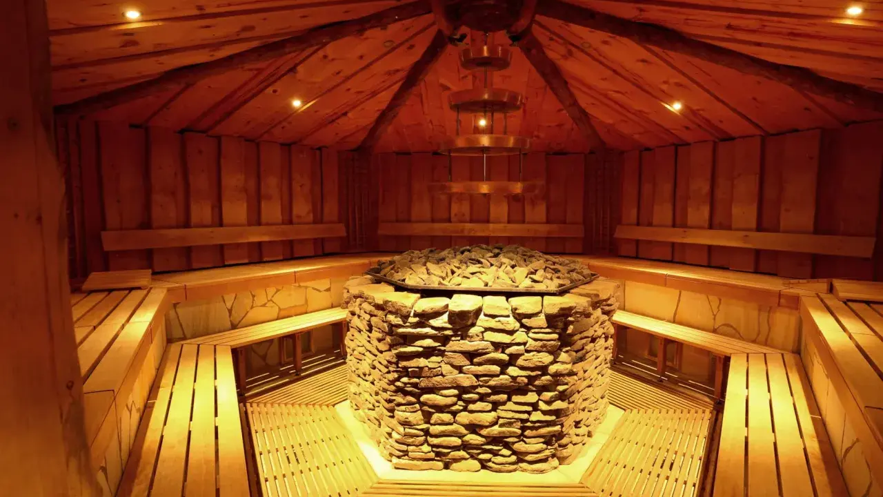 Gemütliche Sauna mit Steinofen und Holzbänken in der Therme Herford. Entspannung pur in rustikalem Ambiente.