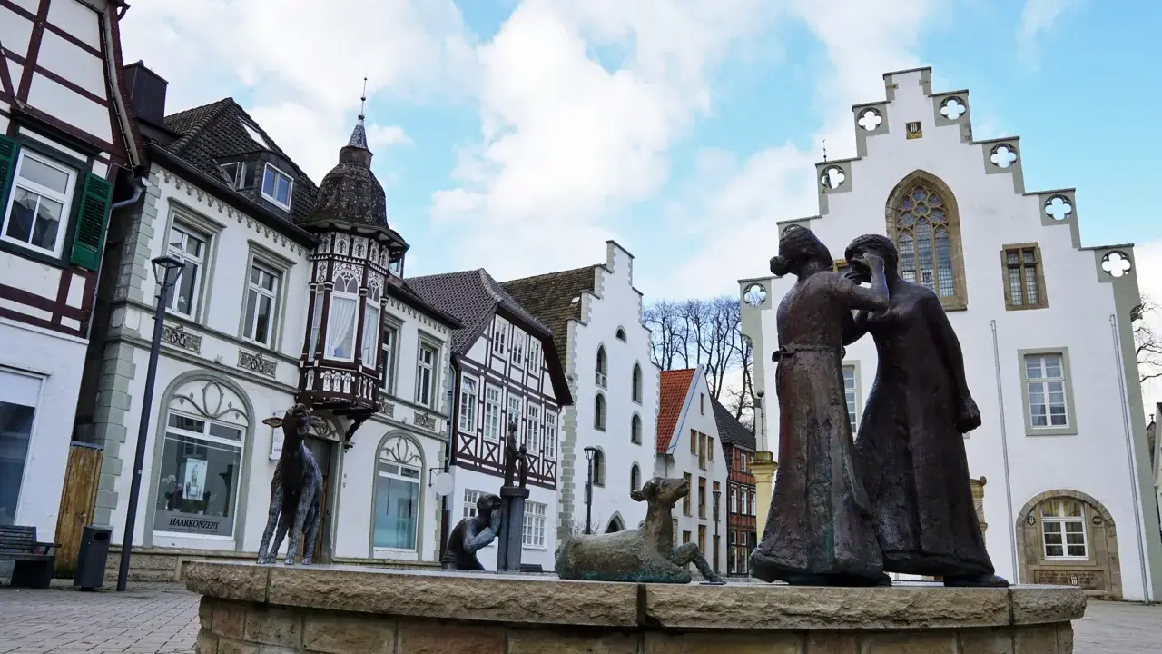Skulpturen auf dem Markt Brakel vor Fachwerkhäusern und einem weißen Giebelhaus.