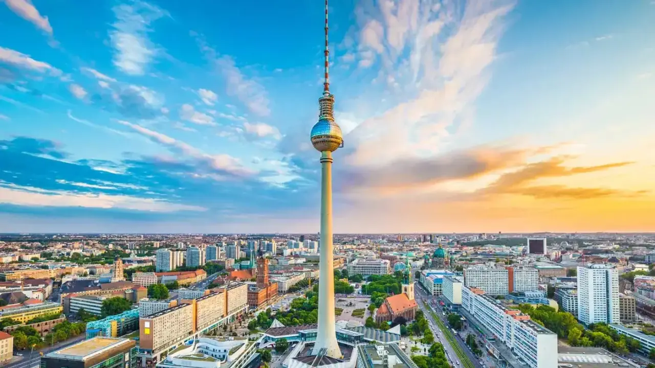 Der Berliner Fernsehturm mit seiner Aussichtsplattform ragt über die Stadt. Ein dramatischer Himmel mit Wolken und Abendsonne umrahmt das Wahrzeichen.