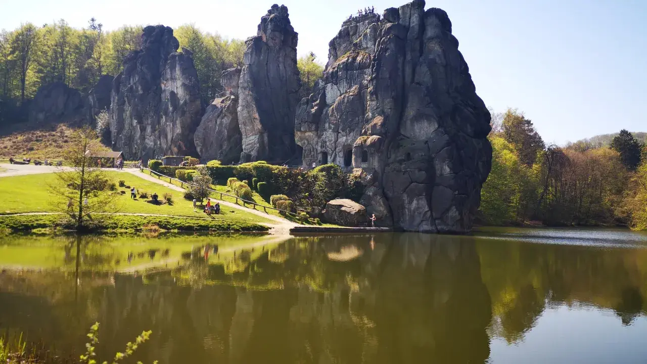 Felsformationen im Teutoburger Wald spiegeln sich in einem ruhigen See. Besucher genießen die Aussicht auf die beeindruckende Natur.