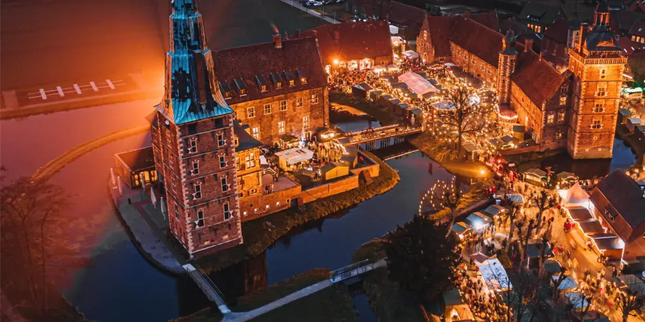Magischer adventsmarkt raesfeld mit beleuchtetem Wasserschloss und vielen Buden.