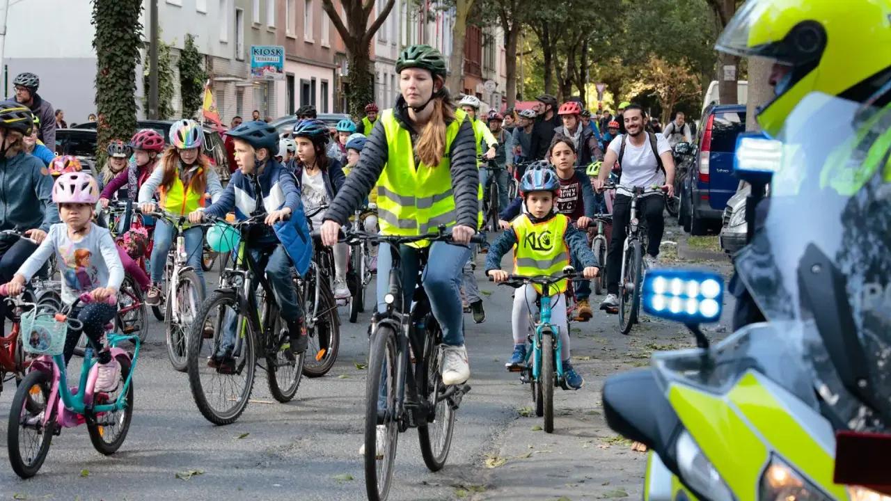 Kinder und Erwachsene radeln bei der Kidical Mass Dortmund. Viele tragen Warnwesten und Helme.