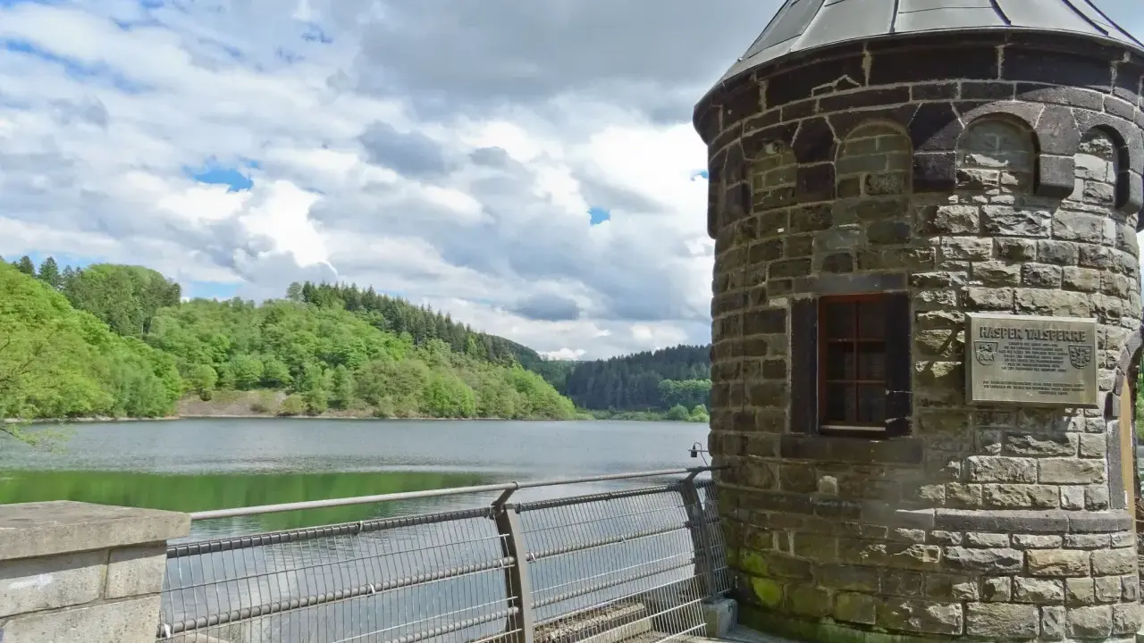 Ein schöner Tag zum spazieren gehen am NRW See. Ein alter Turm steht am Ufer, umgeben von grünen Hügeln und einem ruhigen See.