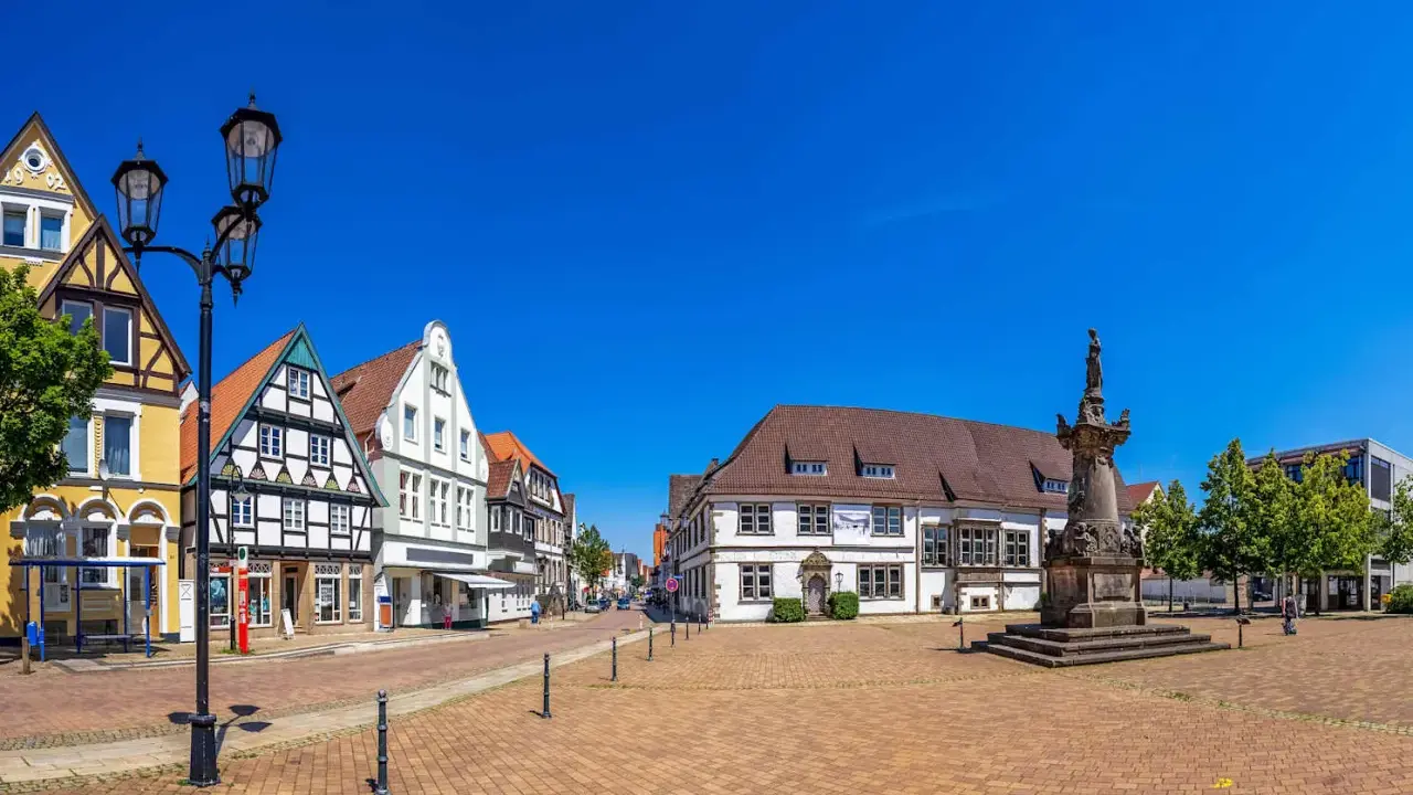 Blick über den Marktplatz der horn-bad meinberg altstadt mit Fachwerkhäusern, einem Denkmal und blauem Himmel.