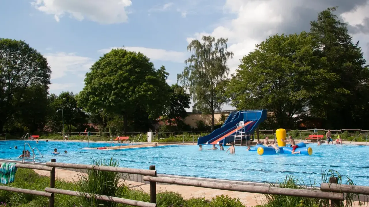 Ein sonniger Tag im Freibad Lahde. Kinder planschen im Wasser, rutschen und spielen auf einem aufblasbaren Spielzeug.