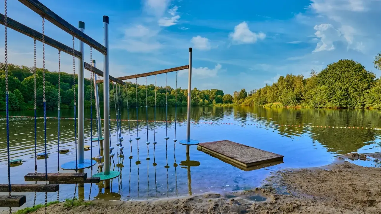 Borken am See: Ein Hindernisparcours im Wasser lädt zum Spielen ein. Der Sandstrand und die grüne Uferkulisse versprechen einen schönen Sommertag.