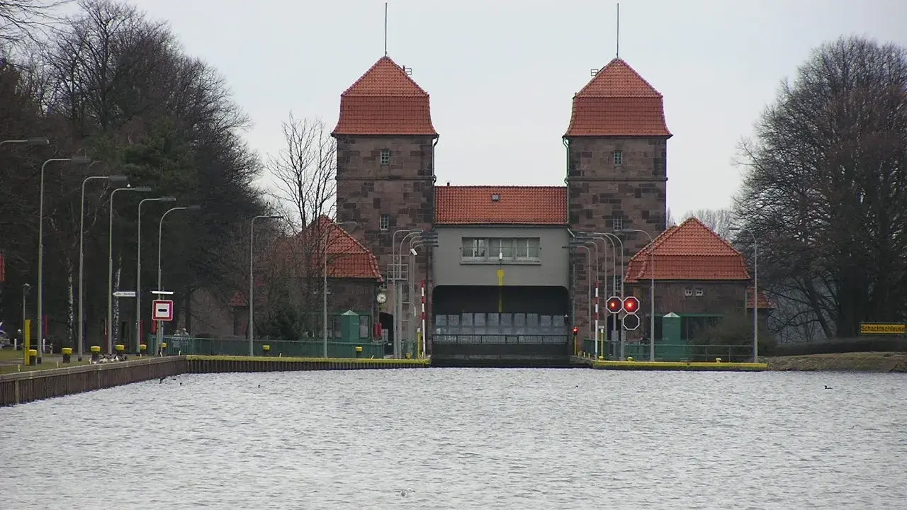 Die Schachtschleuse Minden mit ihren markanten Türmen und roten Ziegeldächern ragt über das ruhige Wasser.
