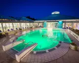 Abendliche Erfrischung im beleuchteten Pool der Therme Bad Driburg. Drei Personen genießen das warme Wasser unter dem klaren Nachthimmel.