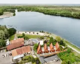 Idyllischer Seeuferbereich mit Sandstrand, Booten und Häusern. Ein perfekter Ort für einen entspannten Seeurlaub in Gronau.