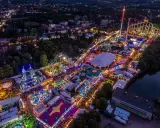 Luftaufnahme eines beleuchteten Volksfestes mit Fahrgeschäften, Zelten und Menschenmassen. Ein typisches Bild für Veranstaltungen NRW.