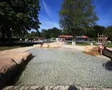Kinder planschen im flachen Wasser des Parkbad Versmold. Eine Rutsche lockt zum Spielen.