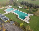 Luftaufnahme des Freibad Gehlenbeck mit Schwimmbecken, Sprungturm und Spielplatz.