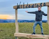 Ein Mann steht vor einem Holzrahmen mit der Aufschrift "Wildewiese". Ein toller Ort für fotospots nrw bei Sonnenuntergang.