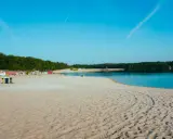 Sonniger Strand in NRW mit feinem Sand, klarem Wasser und grünen Bäumen im Hintergrund. Perfekt für einen entspannten Tag am See.