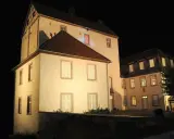 Die beleuchtete Dreckburg in Salzkotten bei Nacht. Ein imposantes Gebäude mit vielen Fenstern und einem dunklen Himmel.