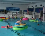 Kinder und Erwachsene planschen im Nichtschwimmerbereich des Schwimmbads Brakel. Viele nutzen bunte Schwimmtiere und Matten.