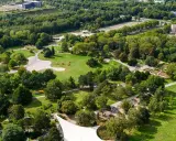 Luftaufnahme eines weitläufigen **Parks in Dortmund** mit grünen Rasenflächen, verschlungenen Wegen, blühenden Beeten und dichtem Baumbestand.