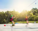 Zwei Kinder üben Wakeboarden am Nesthauser See, gezogen von einer Seilbahn.