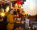 Besucherin auf einem velen Waldweihnachtsmarkt, umgeben von leuchtenden Sternen und weihnachtlicher Deko.