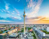 Der Berliner Fernsehturm mit seiner Aussichtsplattform ragt über die Stadt. Ein dramatischer Himmel mit Wolken und Abendsonne umrahmt das Wahrzeichen.
