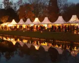 Festliche Zelte am havixbeck weihnachtsmarkt spiegeln sich im Wasser. Besucher bummeln durch die beleuchteten Stände.