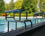 Startblöcke am Beckenrand im Freibad Elverdissen. Das Wasser glitzert, Bäume im Hintergrund.