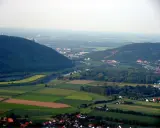 Blick über das Wesertal bei Porta Westfalica mit bewaldeten Hügeln, Feldern und der Stadt.