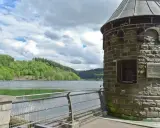 Ein schöner Tag zum spazieren gehen am NRW See. Ein alter Turm steht am Ufer, umgeben von grünen Hügeln und einem ruhigen See.