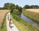 Radfahrer genießen die Fahrt auf dem werse ems radweg entlang eines Kanals und durch Felder.
