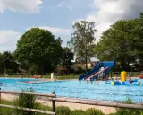 Ein sonniger Tag im Freibad Lahde. Kinder planschen im Wasser, rutschen und spielen auf einem aufblasbaren Spielzeug.