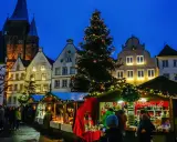 Festlicher Weihnachtsmarkt mit beleuchtetem Baum und Buden vor historischen Häusern. Ein Kandidat für den besten Weihnachtsmarkt NRW.