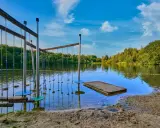 Borken am See: Ein Hindernisparcours im Wasser lädt zum Spielen ein. Der Sandstrand und die grüne Uferkulisse versprechen einen schönen Sommertag.