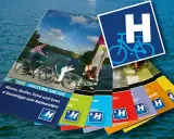 Broschüren für eine Fahrradtour in Haltern am See. Sie zeigen Radfahrer am See und bieten Tourentipps.