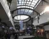 Helles, modernes Einkaufszentrum mit Glasdach. Menschen schlendern durch das Oberhausen Centro, vorbei an Geschäften wie Lacoste.
