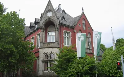 Die Kaiservilla in Minden, ein rotes Backsteingebäude mit Türmchen und zwei GWD-Fahnen, umgeben von üppigem Grün.