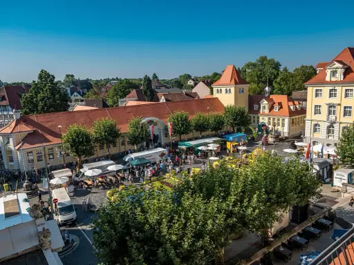 Buntes Treiben auf dem Marktplatz der Herford Innenstadt. Stände, Menschen und Sonnenschein beleben das Bild.