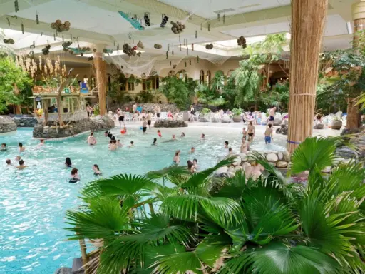 Familien genießen das tropische Ambiente und das Wasser in der **Therme Sauerland**. Palmen und eine Strandbar schaffen Urlaubsfeeling.