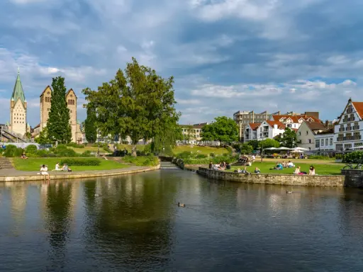 Entspannte Menschen genießen die Sonne am Flussufer in Paderborn. Ein schöner Ort für Paderborn Geheimtipps.