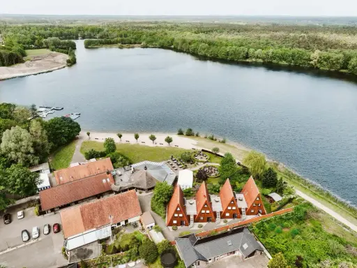 Idyllischer Seeuferbereich mit Sandstrand, Booten und Häusern. Ein perfekter Ort für einen entspannten Seeurlaub in Gronau.