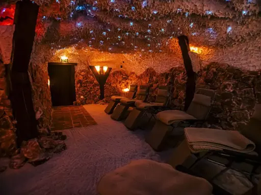 Entspannende Liegestühle in einer **Salzgrotte Paderborn**. Die Wände sind mit Salzsteinen verkleidet, die Decke funkelt mit kleinen Lichtern.
