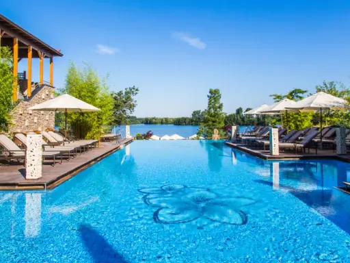 Entspannung pur im Solebad NRW: Ein luxuriöser Pool mit Blick auf den See, umgeben von Bambus und Liegestühlen.