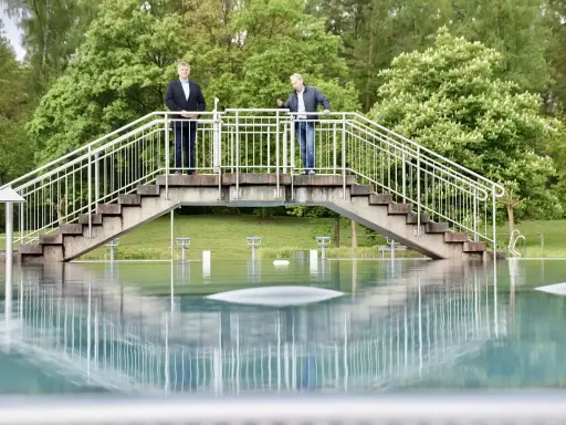 Zwei Männer stehen auf einer Brücke über dem Wasser des Freibad Porta Westfalica.