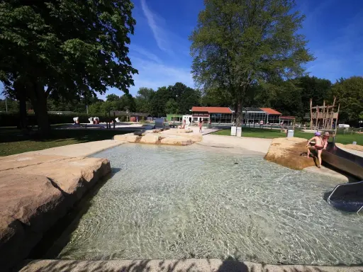 Kinder planschen im flachen Wasser des Parkbad Versmold. Eine Rutsche lockt zum Spielen.