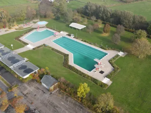 Luftaufnahme des Freibad Gehlenbeck mit Schwimmbecken, Sprungturm und Spielplatz.