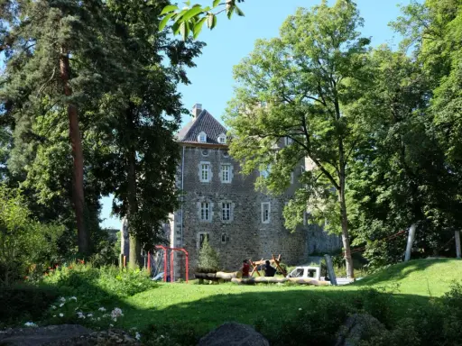 Ein sonniger Tag im Frankenberger Park. Kinder spielen auf einem Spielplatz vor einem alten Gemäuer, umgeben von üppigem Grün.